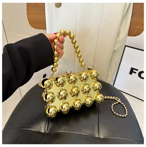 Detailed close-up of golden metallic egg-shell evening bag with beaded handle and chain