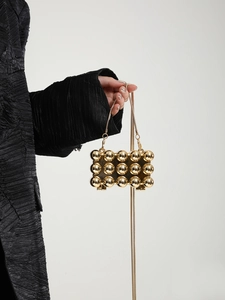 Detail einer goldenen Mini-Clutch aus Metall mit 24 Kugeln und feinem Kettenriemen