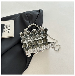 Detail of silver egg-shaped metallic clutch with pearl handle and beaded chain strap