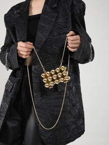 Detailansicht der goldenen Kugel-Mini-Tasche mit Metallkette und glänzender Textur