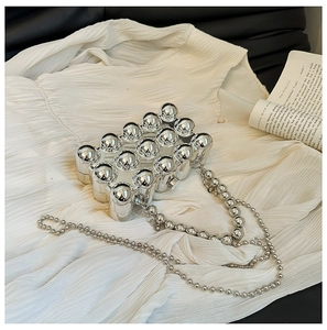Close-up of silver mirror metal clutch bag with 3D beaded texture and ball chain