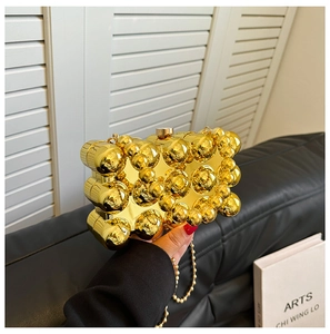 Close-up of golden spherical evening bag with metallic bead texture and bead chain strap
