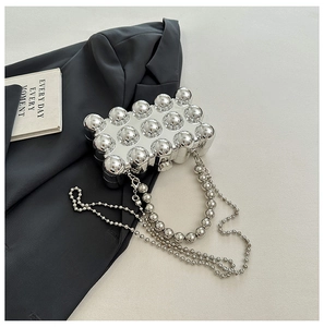Detail of silver metallic dome bag with beaded handle and chain on black suit