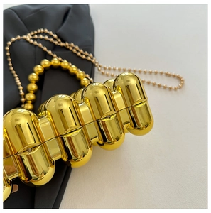 Detailed macro shot of gold egg-shaped evening bag with glossy wavy texture and bead handle