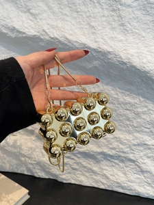 Detailansicht der goldenen Kugel-Tasche mit Metallspiegel-Finish und Kettenriemen