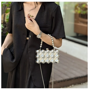 Detail of silver metallic clutch bag featuring 3D spherical texture and beaded handle