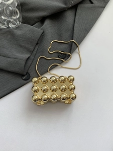 Makroaufnahme der goldenen Kugeltextur und Metallkette der luxuriösen Acryl-Mini-Tasche