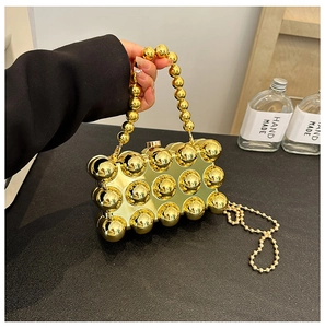 Close-up of golden beaded evening bag with glossy sphere texture and elegant chain strap