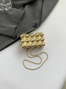 Nahaufnahme der goldenen Metall-Clutch mit Noppenstruktur und eleganter Schlangenkette