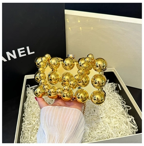 Detail of evening clutch bag with golden mirror metal spheres and fine pearl chain