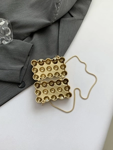 Detail einer goldenen eiförmigen Tasche mit Magnetverschluss und Schlangenkette