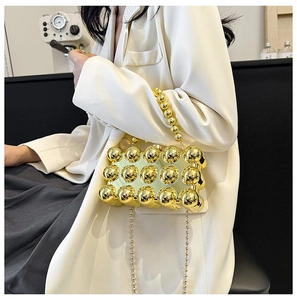 Detail view of a gold metallic beaded dinner bag with a chain strap and a top handle