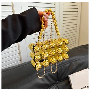 Detail of gold metal ball evening clutch with round bead handle and detachable chain
