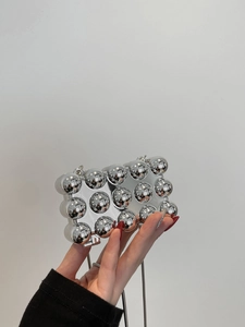 Detail einer silbernen Mini-Kugeltasche mit glänzenden Spiegelkugeln und Metallkette