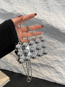 Details der silbernen Mini-Tasche mit Nieten und Schlangenkette in der Hand