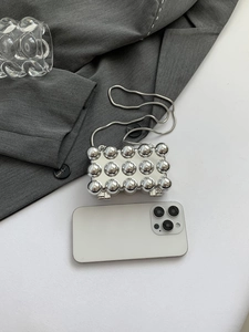 Detail der silbernen Metallic-Hartschalentasche mit 3D-Noppen und Schlangenkette