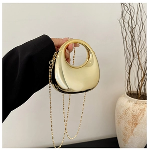 Close-up of a crescent gold metal handbag with mirror finish and elegant bead chain