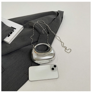 Close-up of mini silver metallic handbag with round handle and beaded chain strap