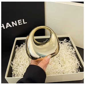 Close-up of golden mirror acrylic evening clutch featuring integrated circular ring handle
