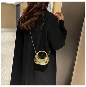 Polished gold semi-circular mini bag with slim chain strap shown on a black blazer