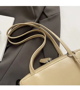 Detail of beige faux leather shoulder bag featuring smooth double straps and metal zipper
