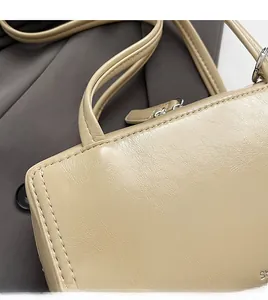 Close-up of beige leather handbag texture showing fine stitching and silver hardware detail