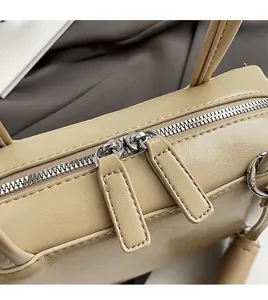 Close-up of smooth silver dual metal zippers and leather pullers on a beige bowling bag