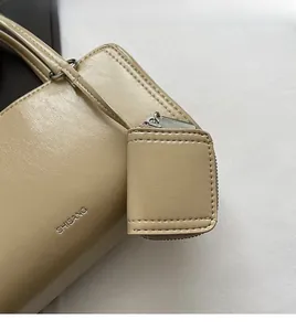 Close-up of cream leather underarm bag featuring a small matching zip coin purse