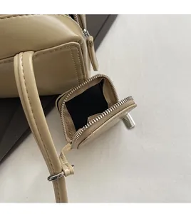 Close-up of beige leather shoulder bag showing smooth texture and open silver zipper pocket