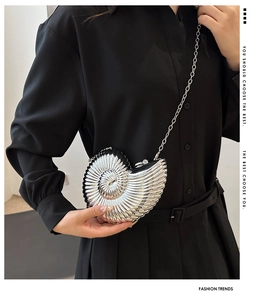 Détail d'une pochette en acrylique argenté en forme de coquille avec rayures et chaîne