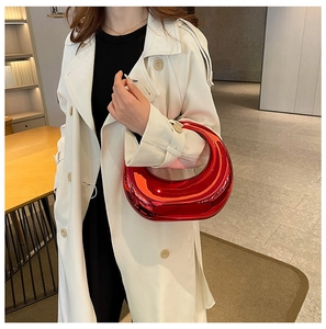 Detalle de un bolso de media luna rojo metálico brillante llevado por una modelo elegante