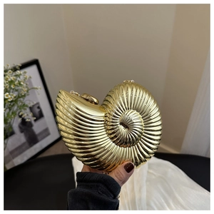 Détail d'un sac pochette doré en forme de conque avec texture spirale et fermoir boule