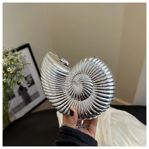 Détail du sac à main argenté en forme de coquille avec chaîne et texture en spirale