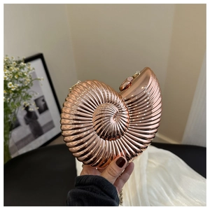 Détail de la pochette nautile en or rose avec texture métallique et bandoulière chaîne