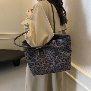 Retro leopard print tote bag with black leather straps shown on model shoulder