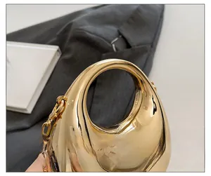 Detail shot of a golden oval evening clutch with smooth electroplated finish and metal chain