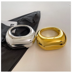 Detalle de bolsos de mano acrílicos brillantes en oro y plata con asas circulares
