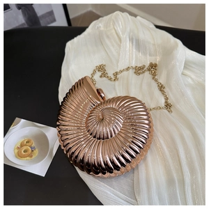 Gros plan d'un sac de soirée en forme de conque or rose avec texture en spirale et chaîne