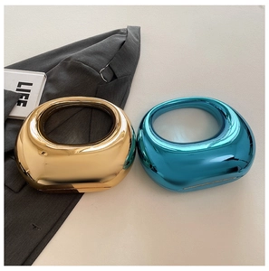 Detalle de bolsos de mano redondos de acrílico en oro metálico y azul eléctrico espejo