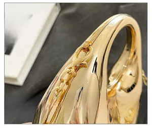 Close-up of golden mirror finish acrylic handbag with thick metal chain and lobster clasp