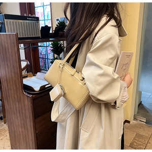 Detail of a beige glossy leather shoulder bag with a matching mini coin purse attachment