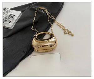 Detailed view of mini gold acrylic crescent evening bag with chain and round handle