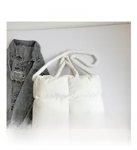 Detail view of white quilted puffer handbag with soft square padded texture and tubular strap