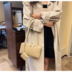 Detail of beige rectangle shoulder bag with matching square coin purse charm and dual handles