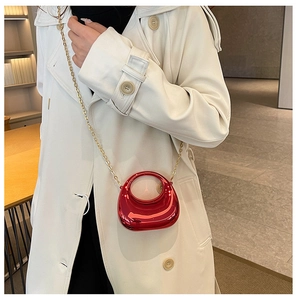 Close-up of mini red crescent bag with gold chain strap on a trench coat model