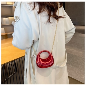 Close-up of bright red mini evening bag with gold chain strap on white coat