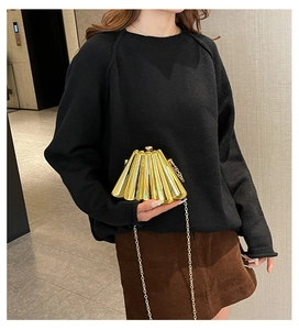 Detail of gold pleated evening clutch bag with chain strap and metallic texture