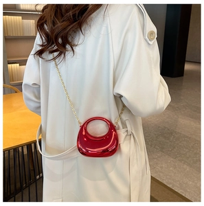 Red metallic crescent mini bag with gold chain worn over an elegant cream trench coat