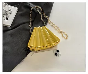 Detailed macro view of the gold pleated metal evening clutch bag with chain strap