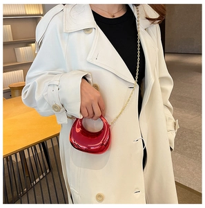 Red metallic crescent mini bag with gold chain shown on a white double-breasted coat